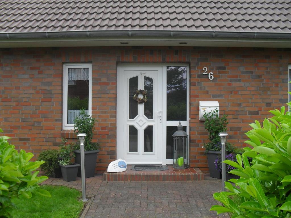 ein Backsteinhaus mit einer weißen Tür mit einem Kranz darauf in der Unterkunft Ferienwohnung Geli in Tönning