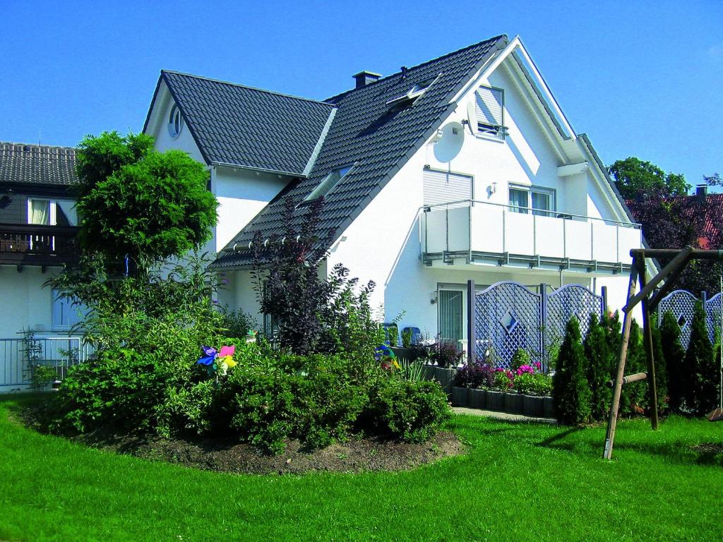 Biały dom z czarnym dachem i kwiatami w obiekcie Albrecht-Jäger Fewo w mieście Bad Sassendorf