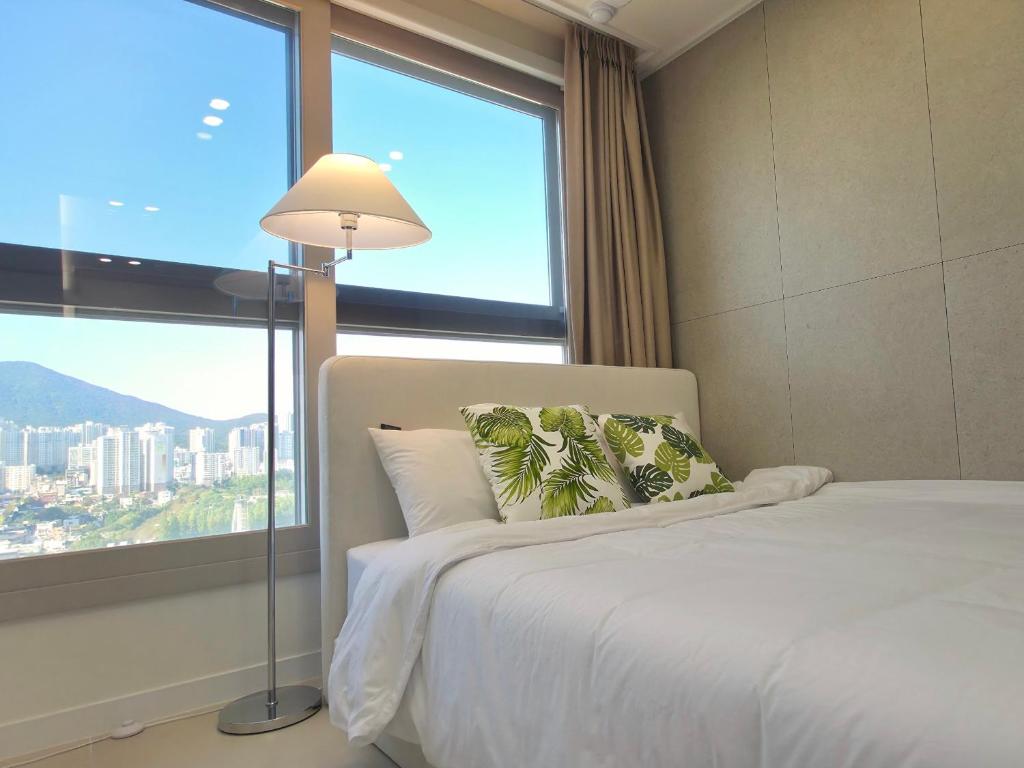 a bedroom with a bed and a large window at 부산 서면 레지던스 신축 힐링 하우스 in Busan