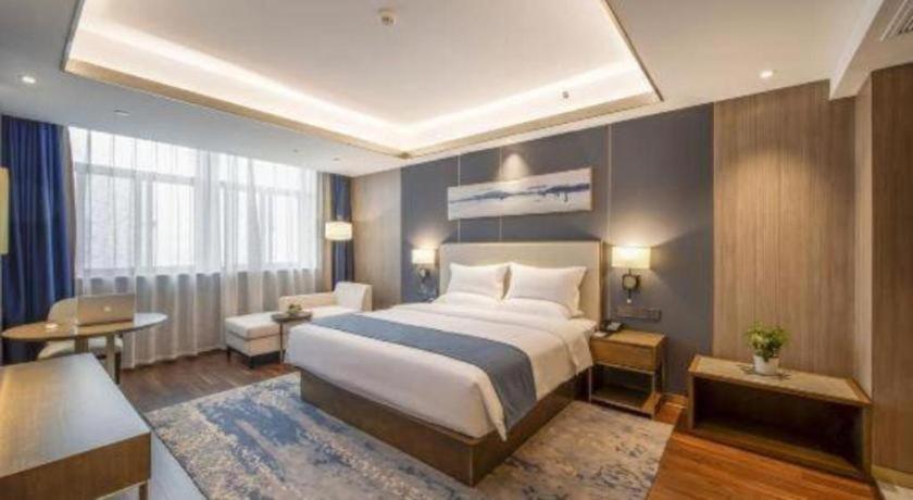a hotel room with a large bed and a desk at The Long Red Hotel Daye Huangshi in Huangshi