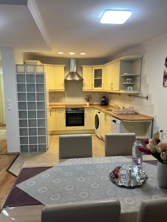 a kitchen with yellow cabinets and a table with chairs at Viva Apartman in Nyíregyháza
