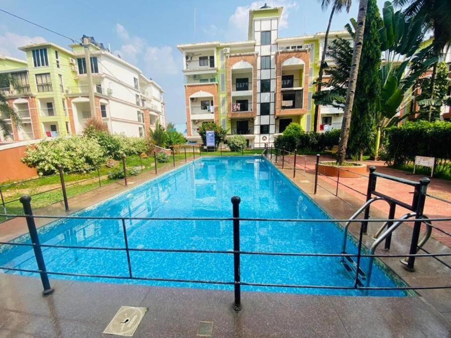 a large blue swimming pool in front of some buildings at Luxury 2BHK Apartment Near Candolim Beach in Candolim