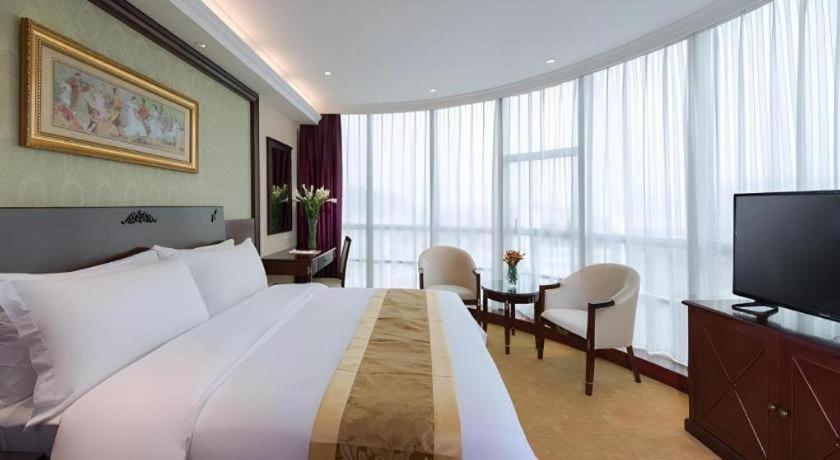 une chambre d'hôtel avec un grand lit et une télévision à écran plat dans l'établissement Vienna 3 Best Hotel Dongguan Fenggang Yongsheng Street, à Tiantangwei