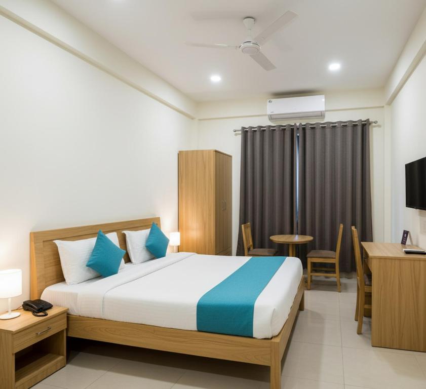 a hotel room with a bed and a desk and a table at Premiere Suites - Brookfield in Bengaluru