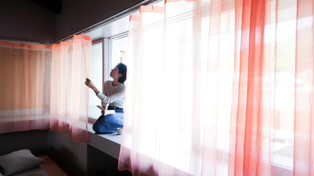 a woman sitting on a window sill looking out at SEW STAY Slow Seam KYOTO MAIZURU in Maizuru
