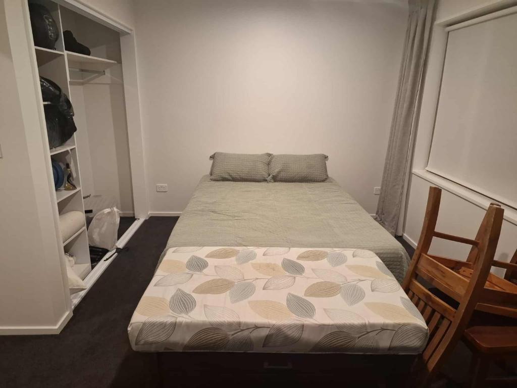 Un dormitorio con una cama y una silla dentro. en The Mews, en Rolleston