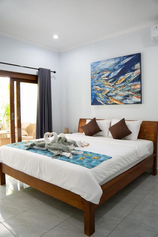 a bedroom with a bed with a painting on the wall at Holiday Guest House in Amed