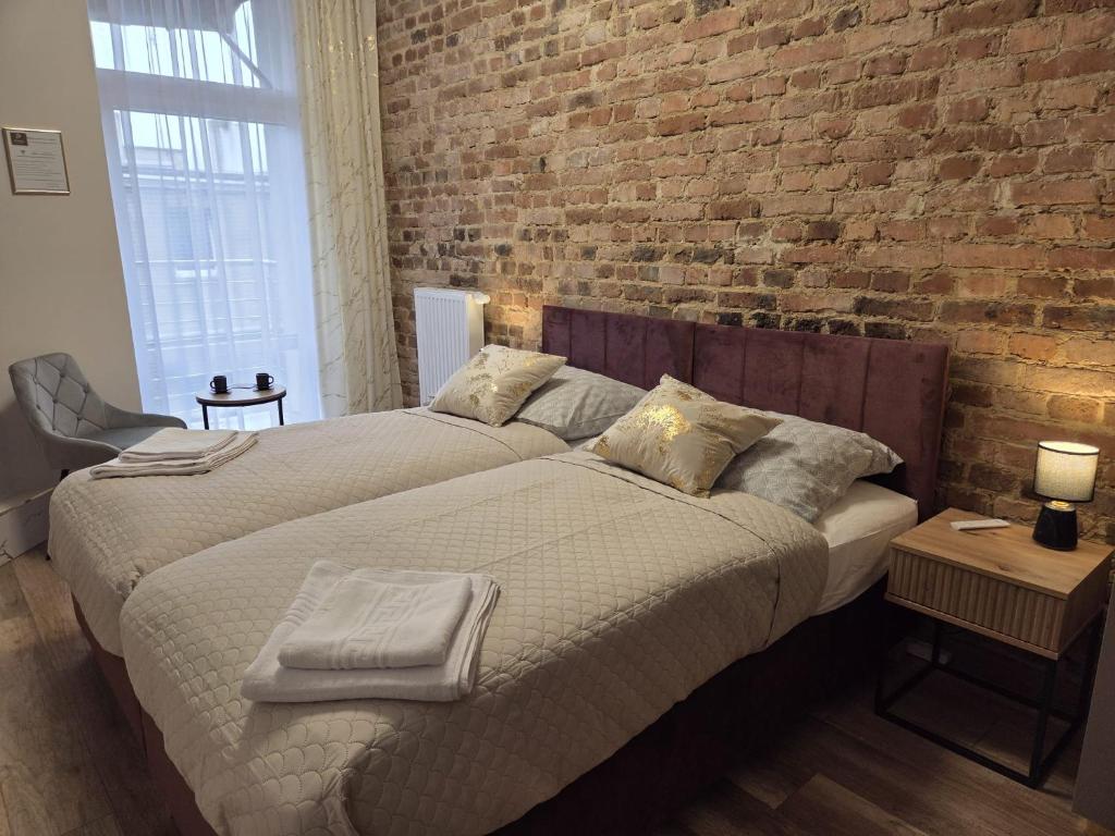 two beds in a bedroom with a brick wall at Placeo in Katowice