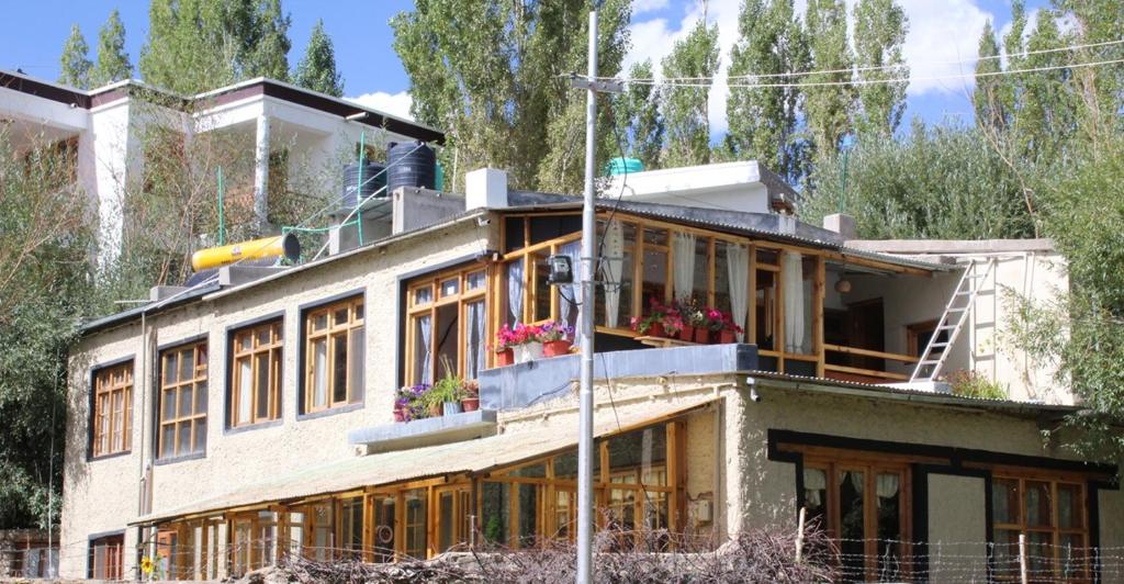 Un edificio con ventanas y flores encima. en Karma Lodge Leh, en Leh