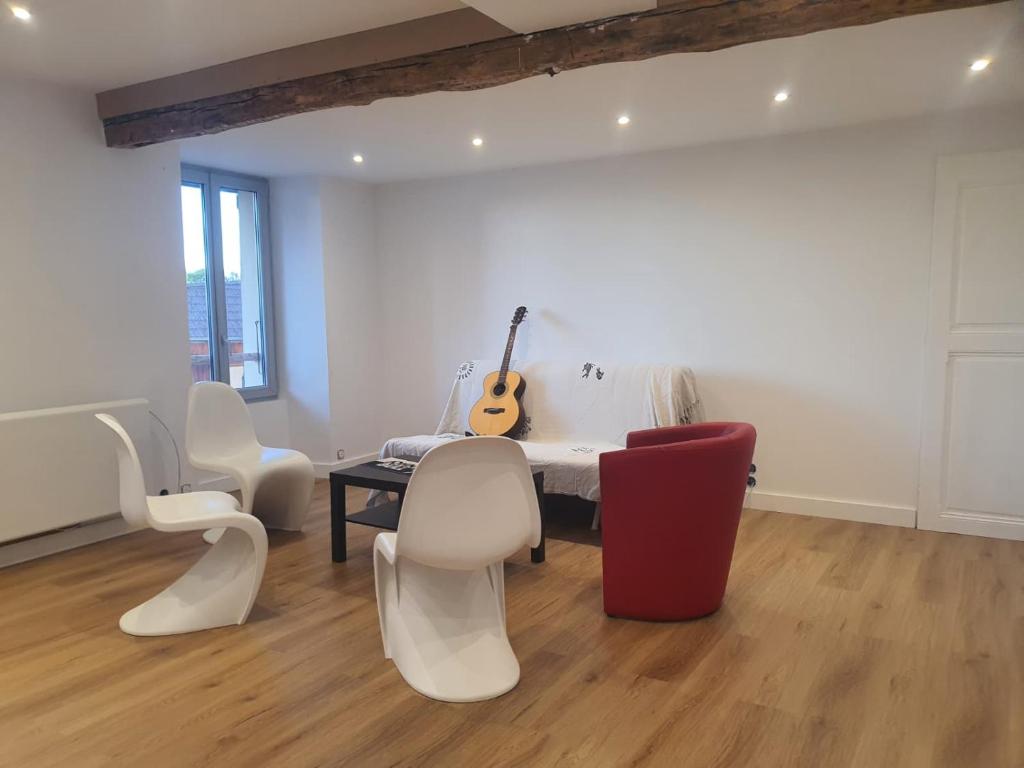 a room with a table with a guitar and chairs at Appartement entier in Izeaux