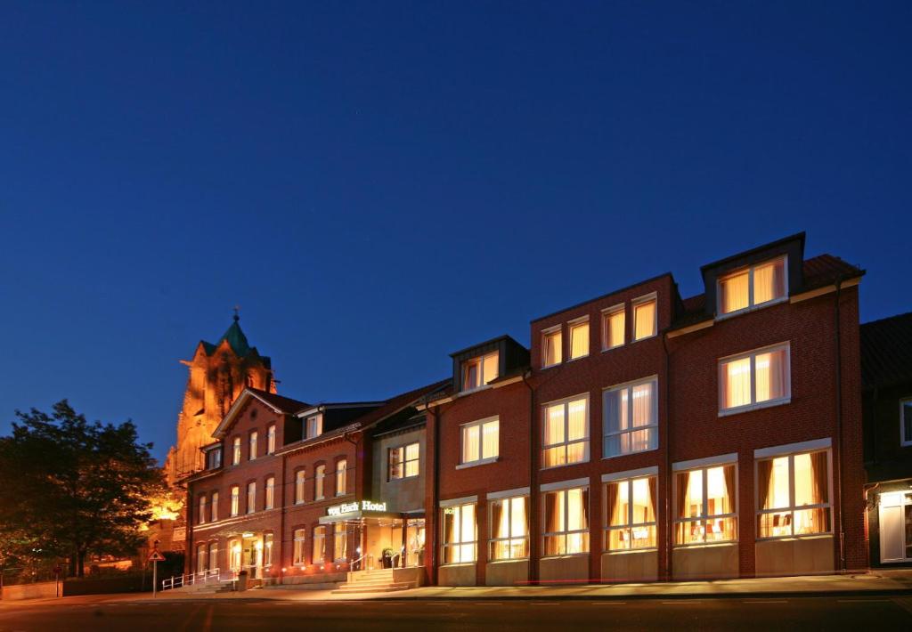 a large brick building with a church in the background at Hotel von Euch in Meppen