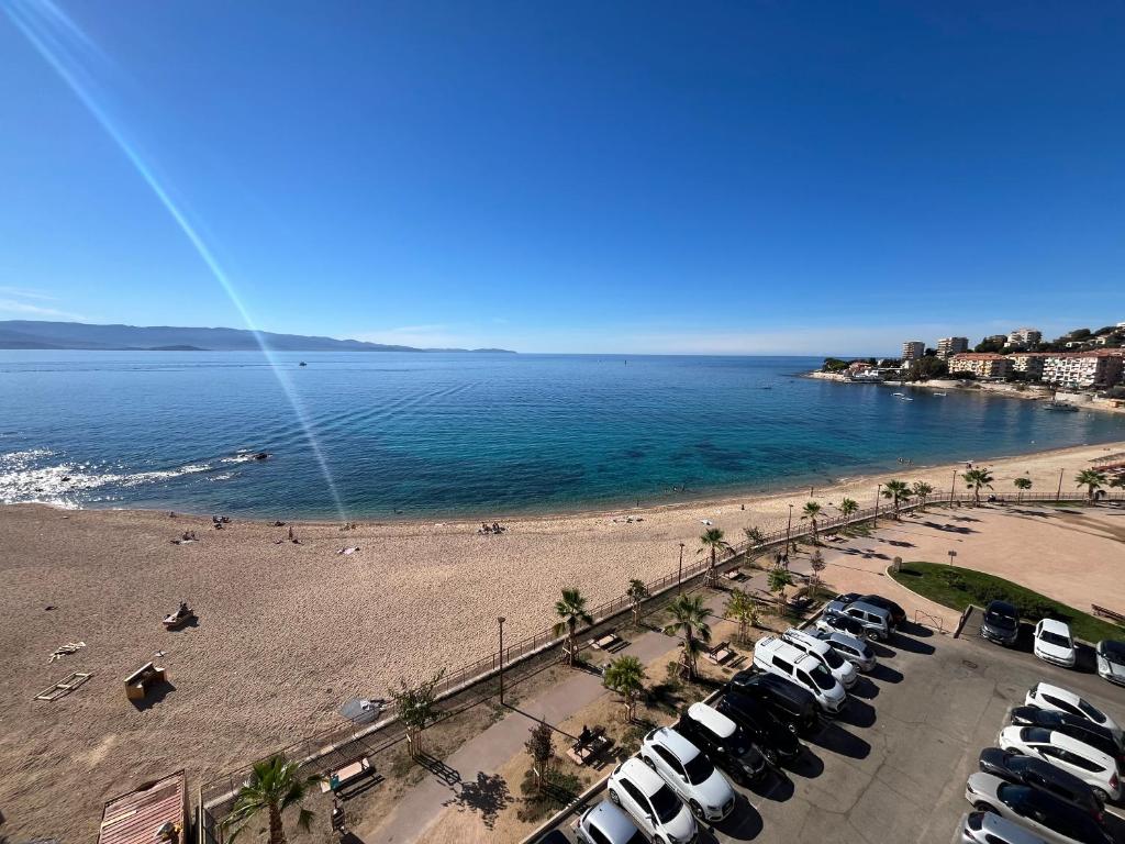 a beach with a bunch of cars parked next to the water at Le Face à La Mer in Ajaccio