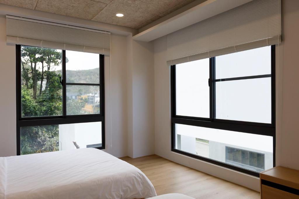 a bedroom with large windows and a white bed at 浪浪別館 Lang lang retreat in Taitung City