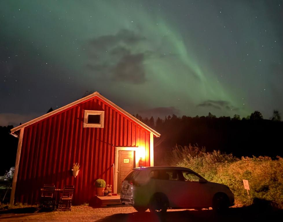 a car parked in front of a red barn at night at Folkja gård i Höga kusten in Noraström