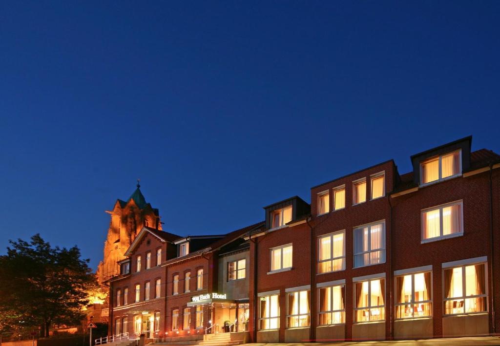 un edificio con una iglesia al fondo por la noche en Hotel von Euch, en Meppen