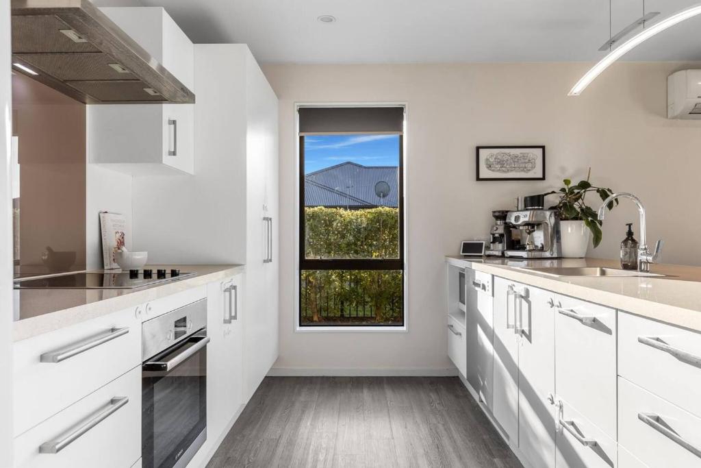 a kitchen with white cabinets and a window at Queen Bed with Private Bath TV kitchen access and one Parking in Rolleston