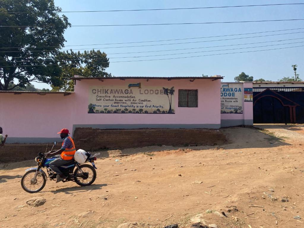 una persona que conduce una motocicleta frente a un edificio en Chikawaga Lodge, en Blantyre
