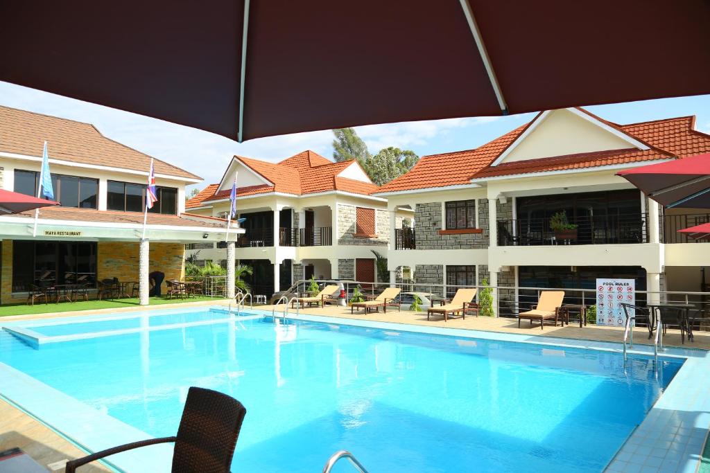 a large swimming pool with chairs and an umbrella at SixPoint Victoria in Kisumu