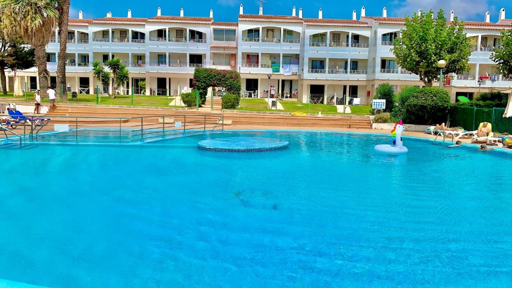 a large swimming pool in front of a large building at SA CALETA - Apartamento con piscina y junto a la playa in Cala en Blanes