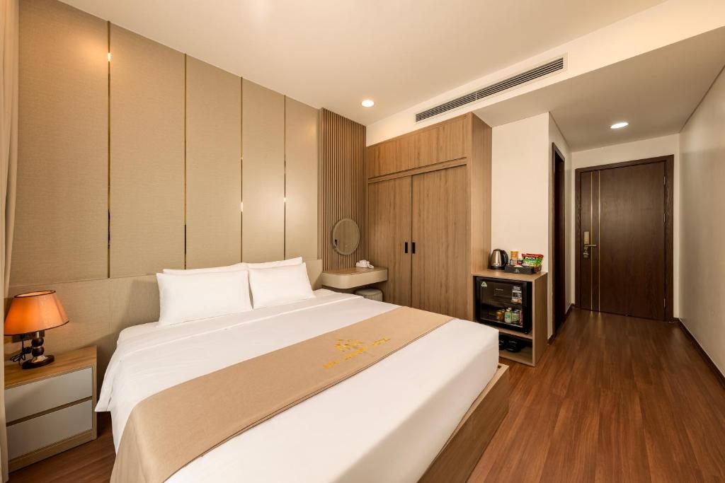 a bedroom with a large white bed and wooden cabinets at MAI Luxury Hotel Ninh Binh in Ninh Binh