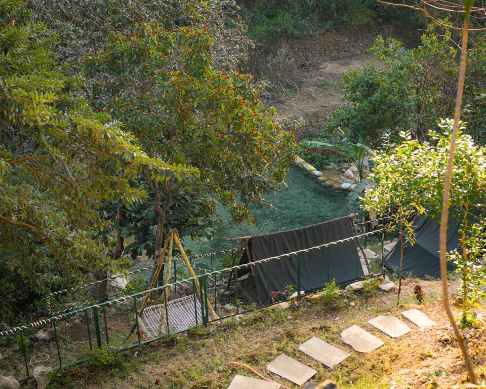 a view of a river with a fence and trees at Green River Camp in Rishīkesh