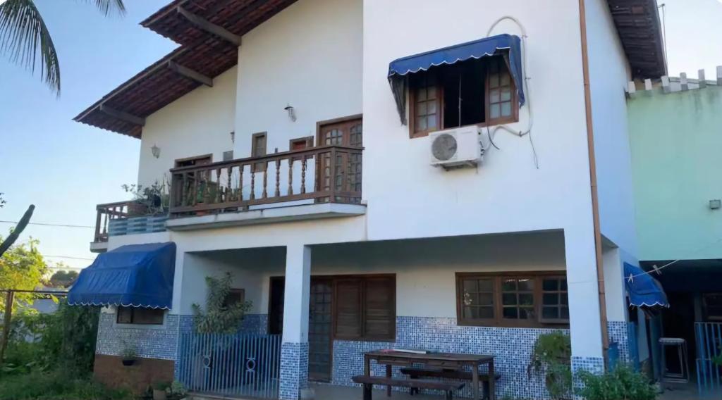 a white house with a balcony and a table at Lar dos Bem-ti-vis in Niterói