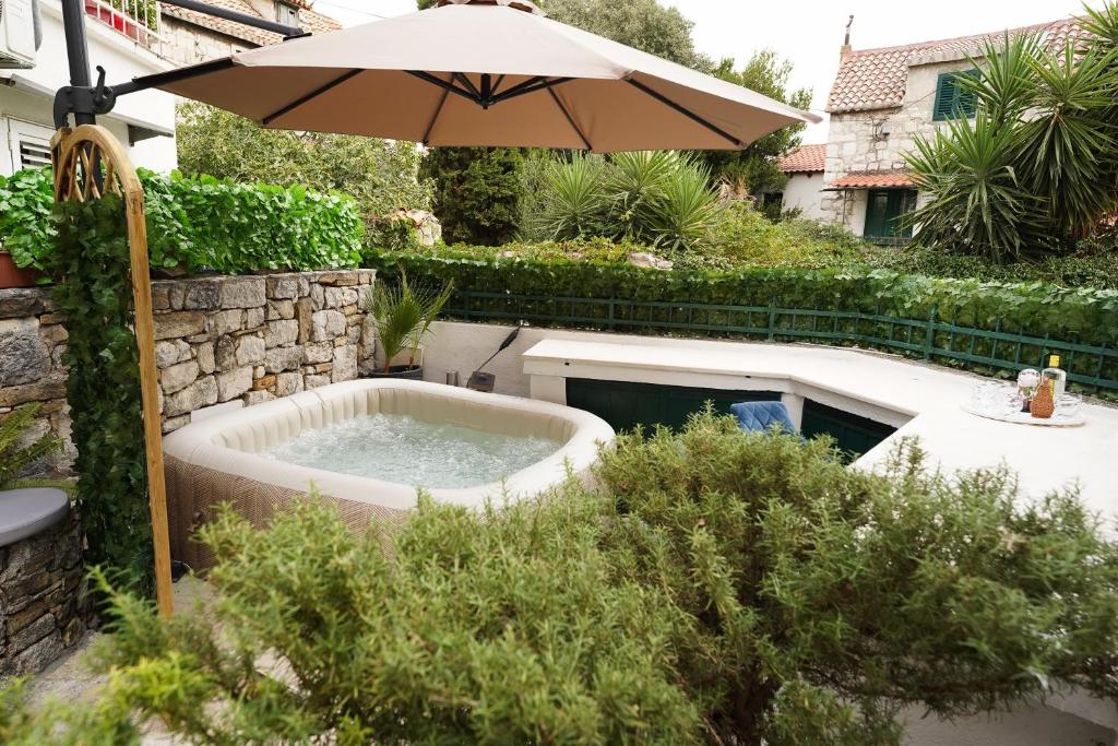 a hot tub in a garden with an umbrella at Villa Stone Garden Escape with jacuzzi in Split