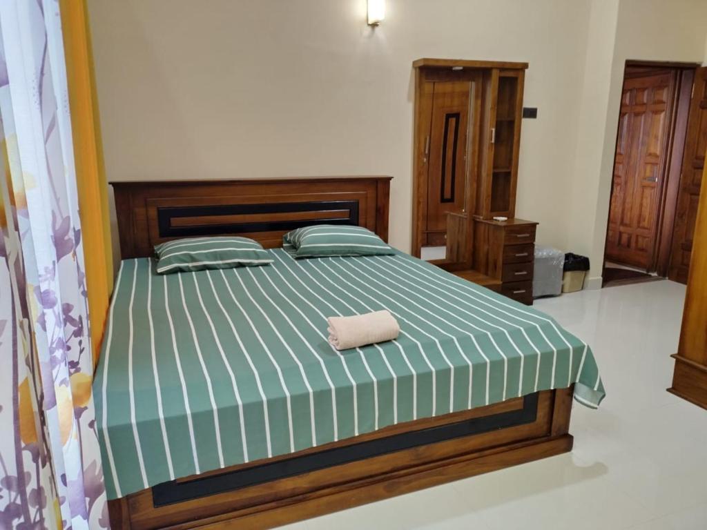 a bedroom with a bed with a green and white comforter at Scenic Lanka Luxury Rooms in Dehiwala