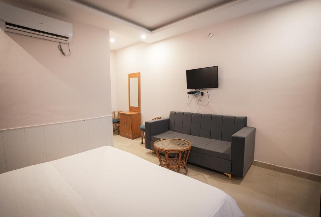 a bedroom with a couch and a tv on the wall at Shaanti Coliving in Rishīkesh