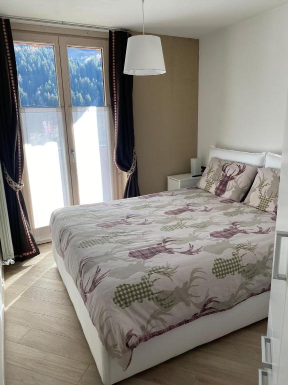 a bedroom with a large bed with a comforter at Relax Mountain Apartments in Isolaccia