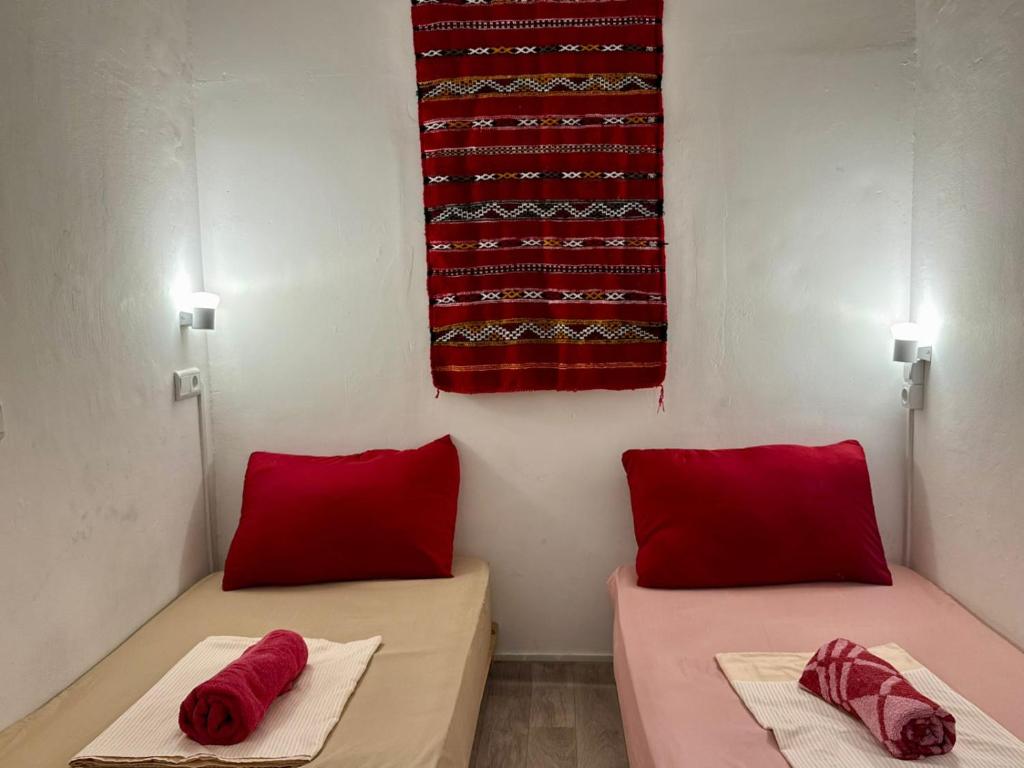 deux lits dans une chambre avec des oreillers rouges et un drapeau dans l'établissement Booon, à Rabat