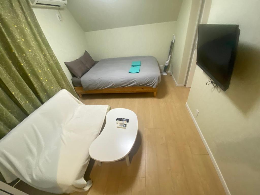 a small room with a bed and a tv at フィフティーフォージャーニー新宿戸山 in Tokyo