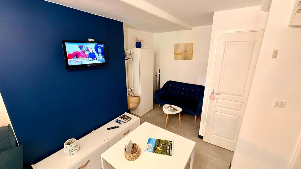 a living room with a tv on a blue wall at Les Cimes au cœur du Massif du Sancy in Le Mont-Dore