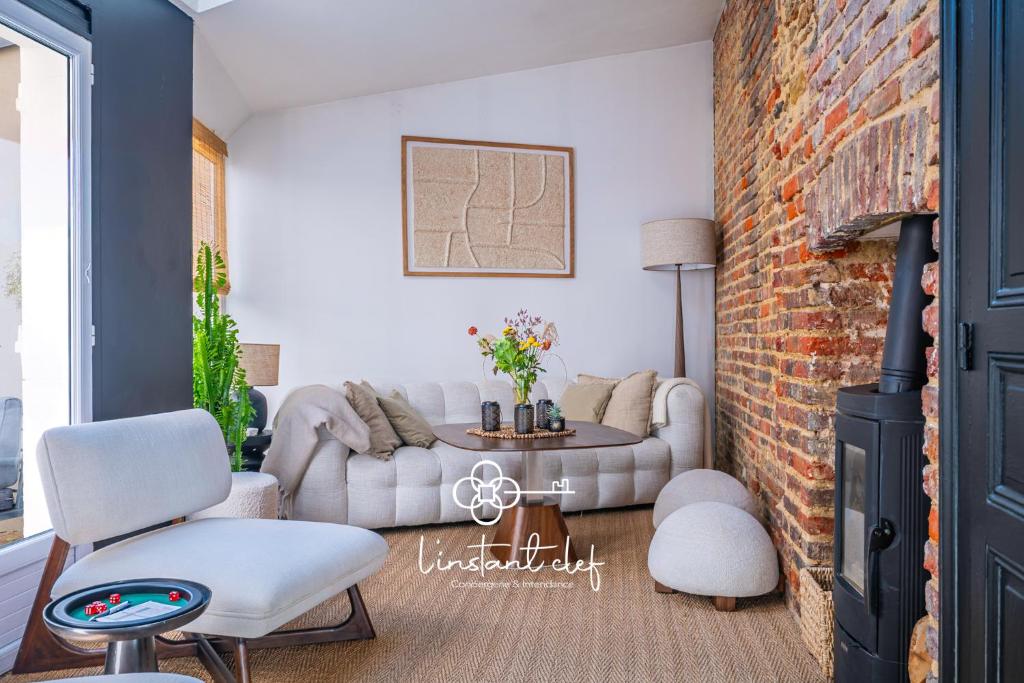 ein Wohnzimmer mit einer Couch und einer Ziegelwand in der Unterkunft Havre de paix avec jacuzzi - Hyper-centre du Mans in Le Mans