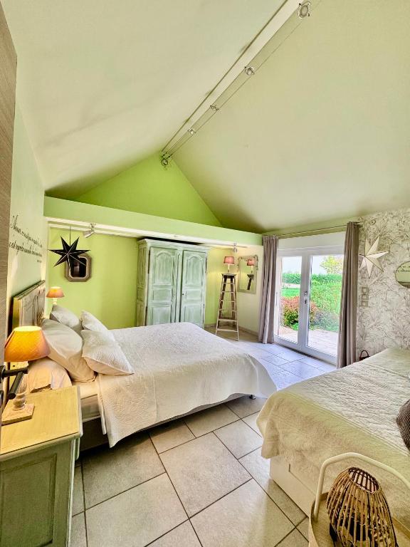 a green bedroom with two beds and a window at Gîte de la Valière in Chevigny-en-Valière