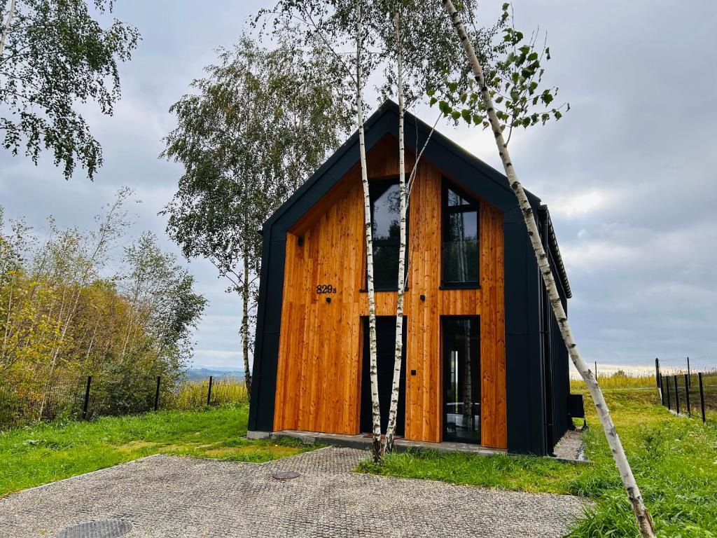 a small black and wooden house in a field at Brzozowy Rożnów in Rożnów