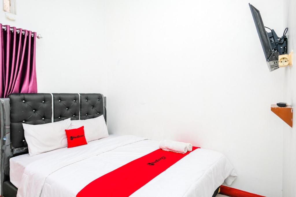 a bed with a red and white blanket on it at RedDoorz Syariah near Alun Alun Wonosobo 4 in Kalianget