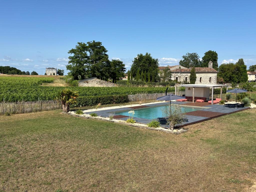 a swimming pool in a yard next to a house at Chambres au cœur des vignes in Saint-Christoly-Médoc