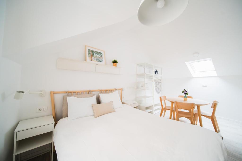 ein weißes Schlafzimmer mit einem Bett und einem Tisch in der Unterkunft Blu Riva Hvar in Hvar