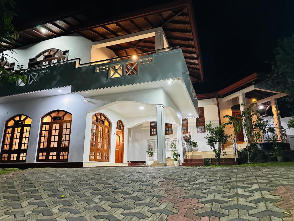 a large white house with a balcony at night at Kashmir villa in Galle
