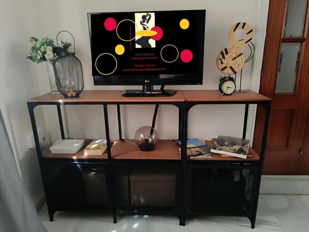 a tv sitting on a stand with a table at Casa Flamenca in Castilleja de la Cuesta