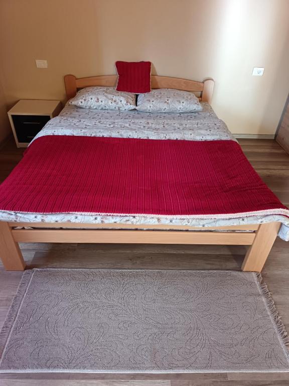 a bed with a red blanket on top of it at Mona apartman in Žabljak