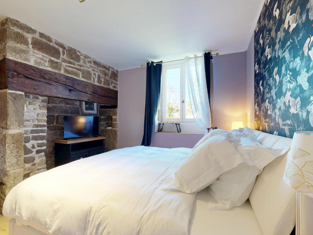 una camera da letto con un letto grande e un muro di pietra di Appartement Standing Sauna Privé a Brive-la-Gaillarde