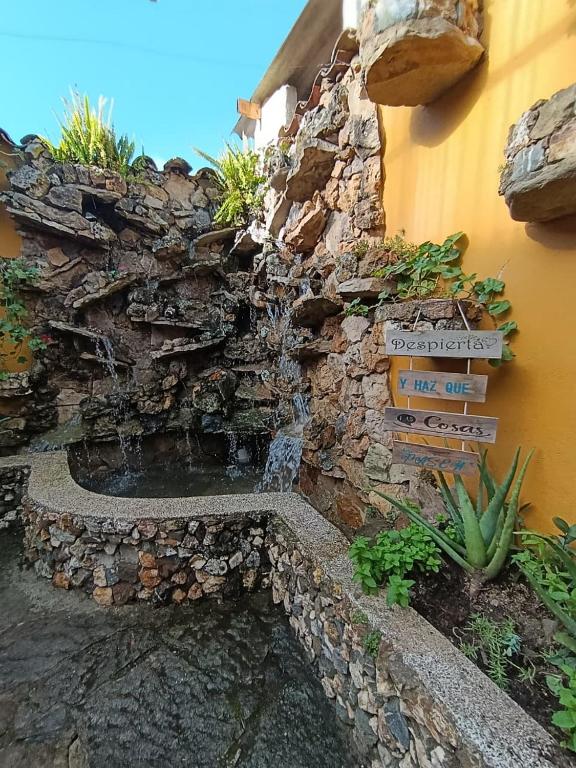 a stone wall with a waterfall in front of a building at Hospedaje La Fuente in Estación El Salto
