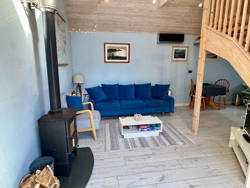 a living room with a blue couch and a stove at The Langland Loft - Tiny Home in The Mumbles