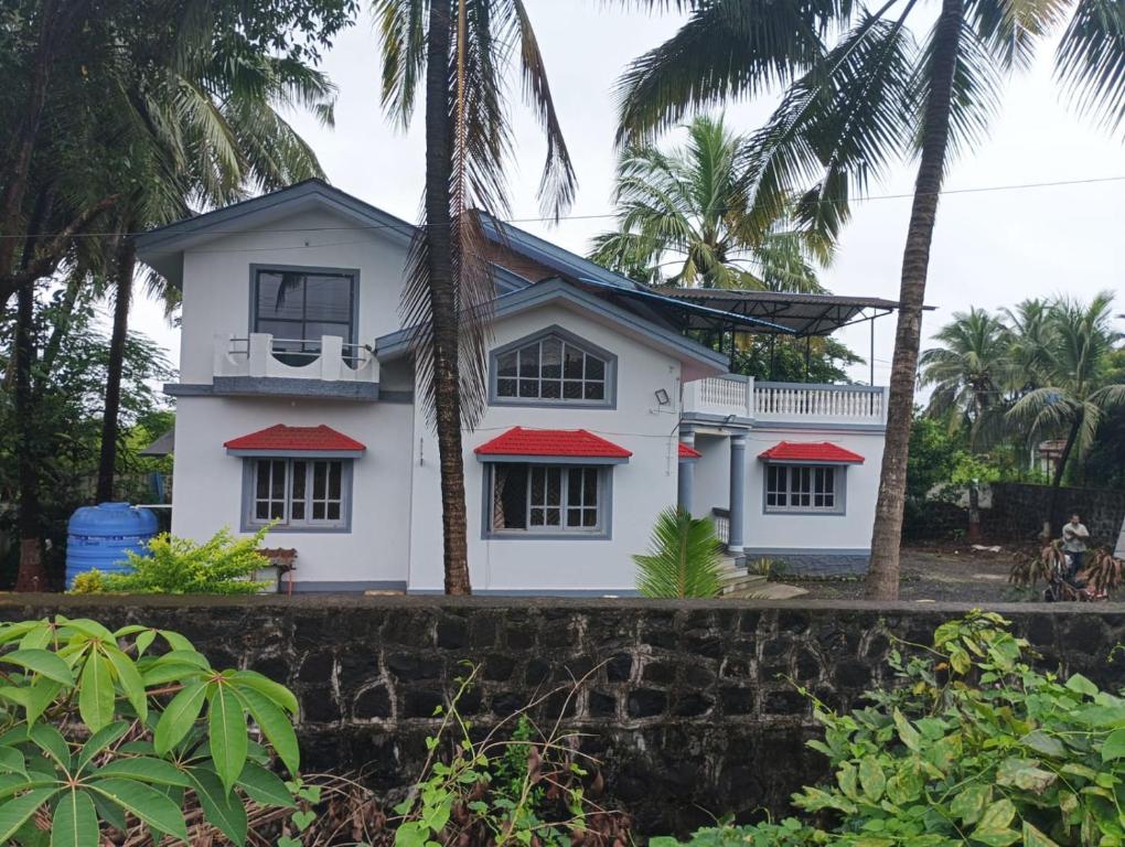a white house with red roofs and palm trees at Peace Villa with pool in Murud