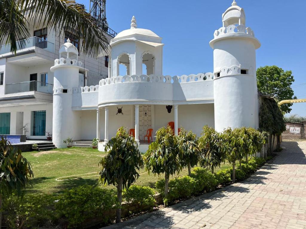 ein großes weißes Haus mit Bäumen davor in der Unterkunft Ashoka Resort in Begusarai