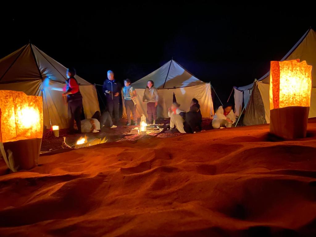 a group of people standing in front of tents at Desert Mhamid in Mhamid