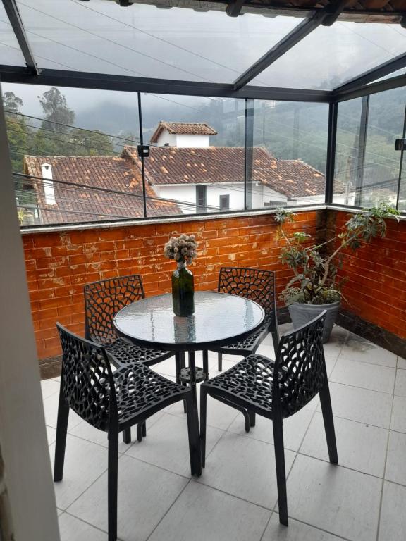 a table and chairs on a patio with a window at Casa em Petrópolis in Petrópolis