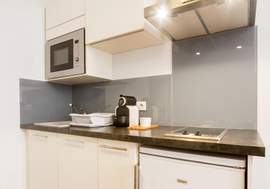 a kitchen with white cabinets and a microwave at Les Loges des Chalets in Toulouse